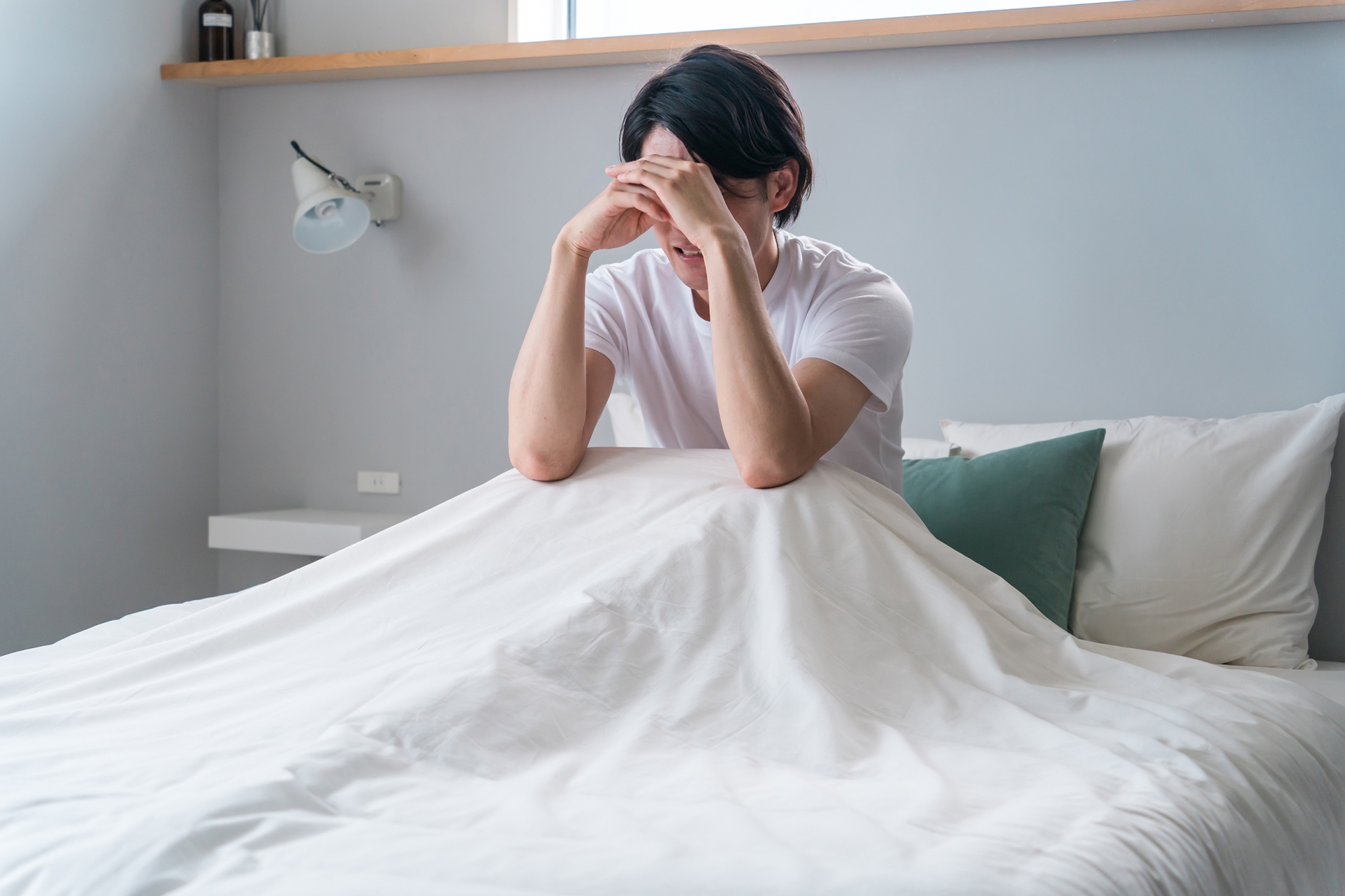 ベッドの上で落ち込む男性